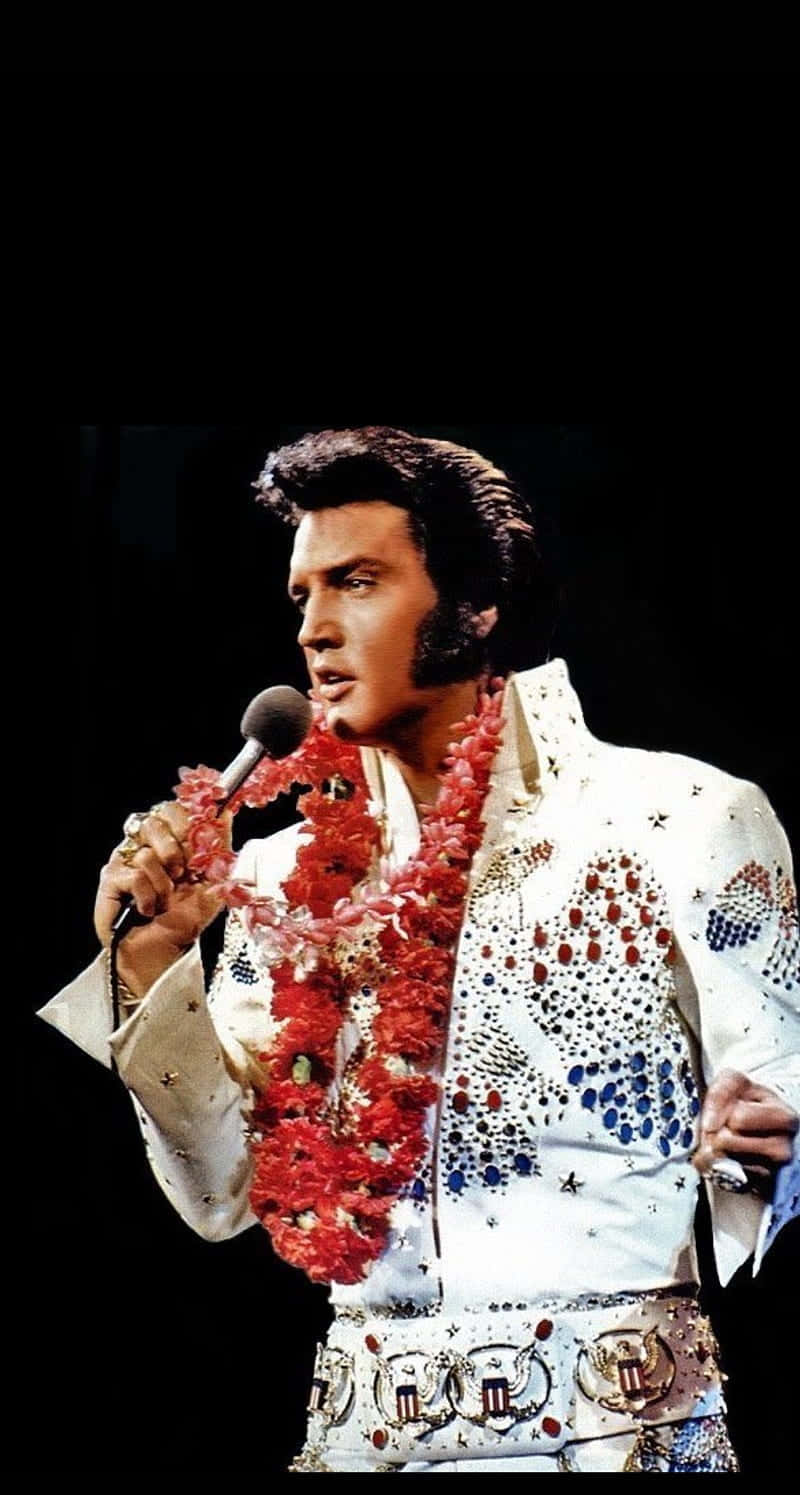 Elvis Presley i en hvid kjole, der synger ind i et mikrofon. Wallpaper