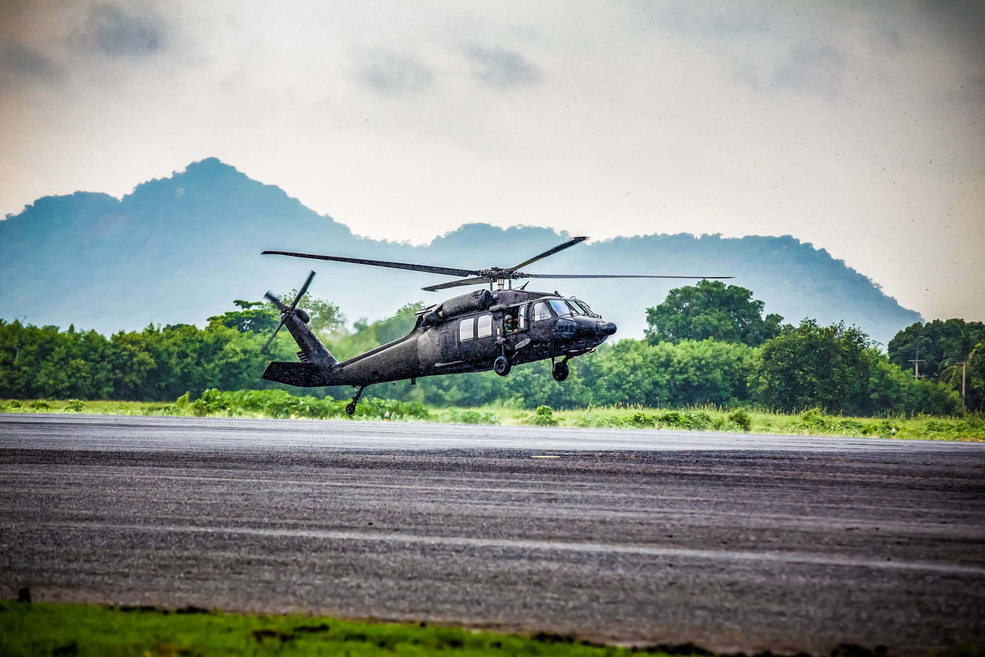 A Black Helicopter Is Taking Off From An Airport Runway