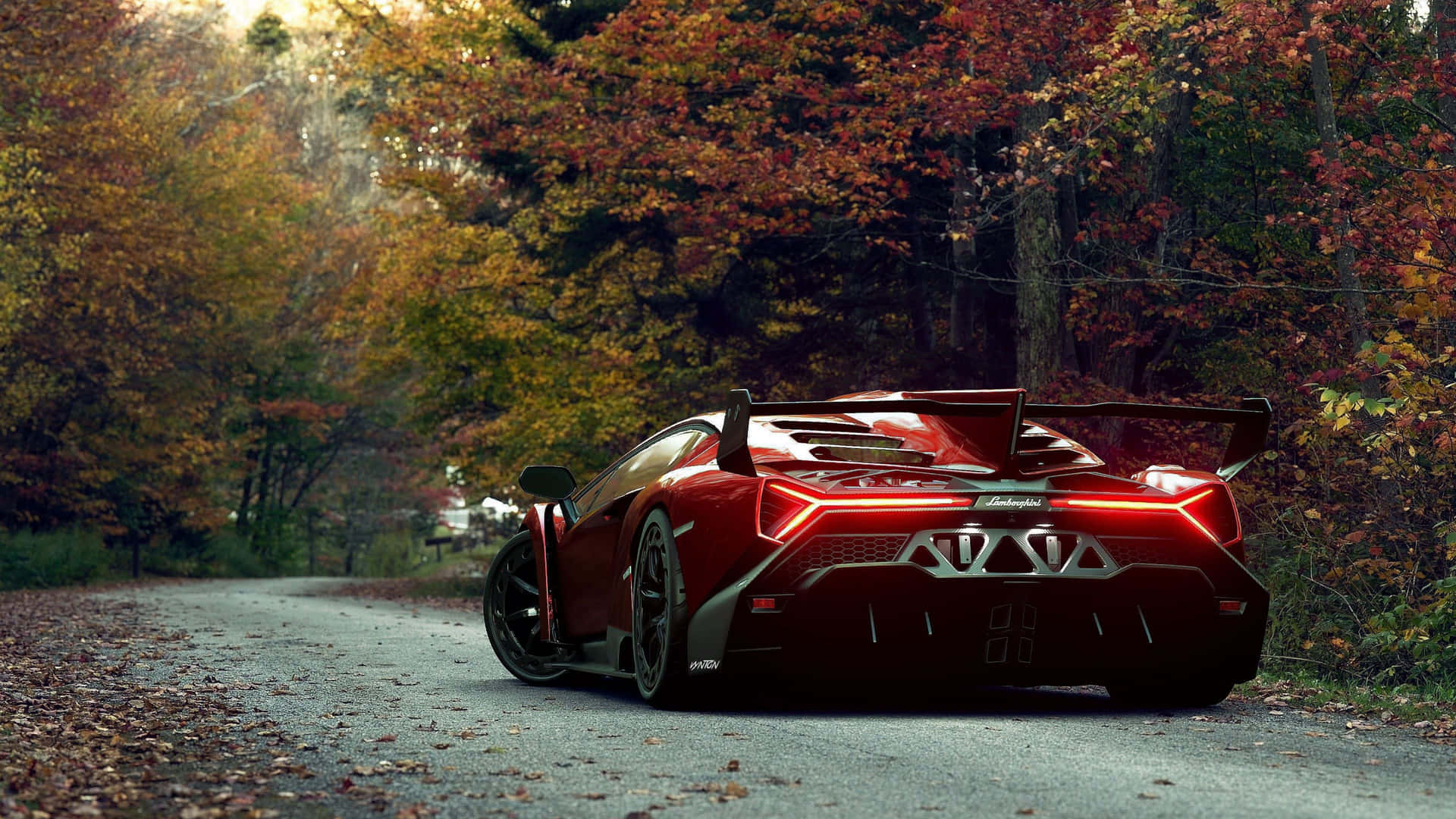 A Red Sports Car Driving Down A Road In The Fall