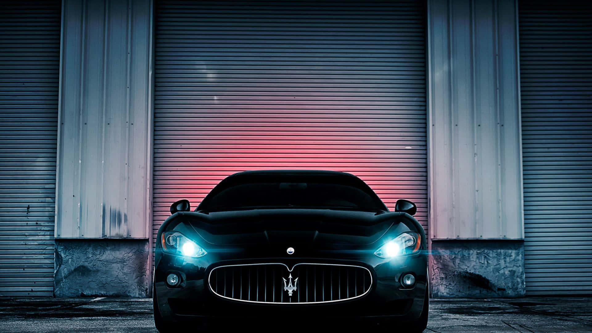 A Black Maserati Parked In Front Of A Garage Wallpaper