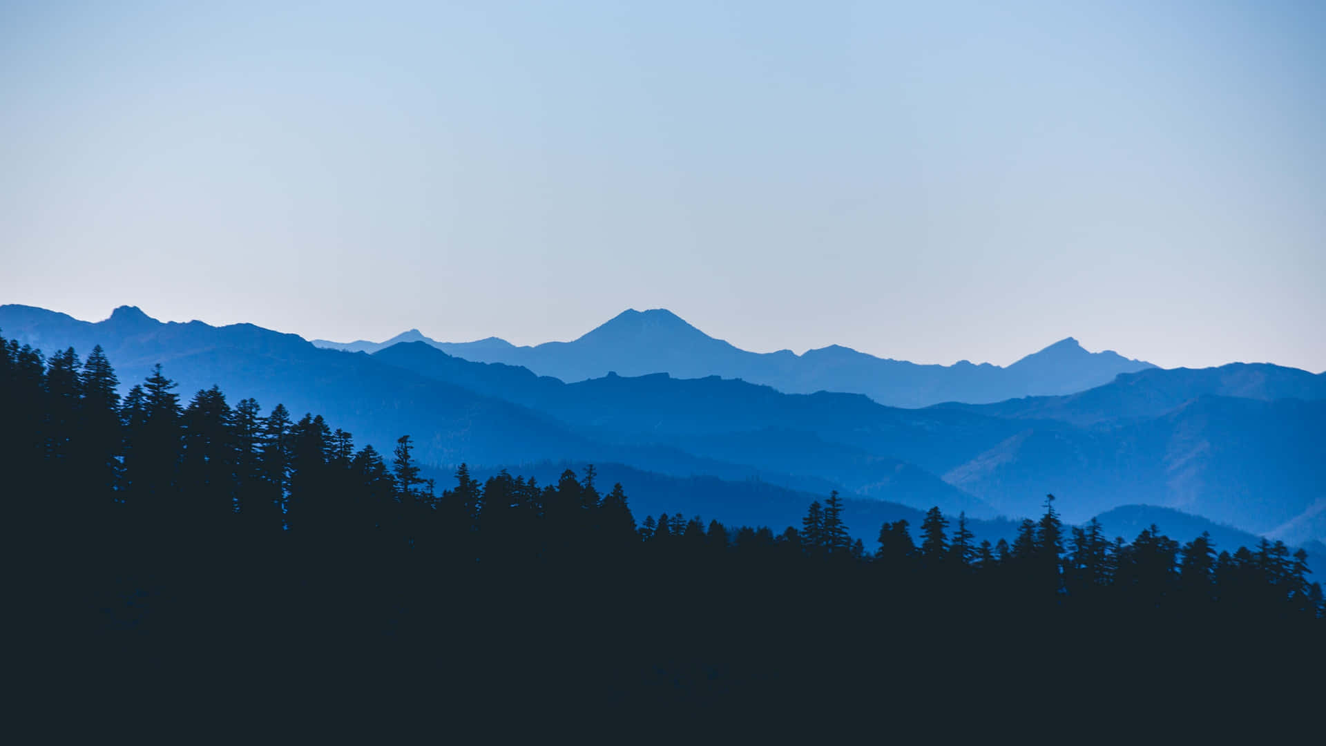 Rangosde Montañas Minimalistas Azules En 4k Con Siluetas De Árboles. Fondo de pantalla