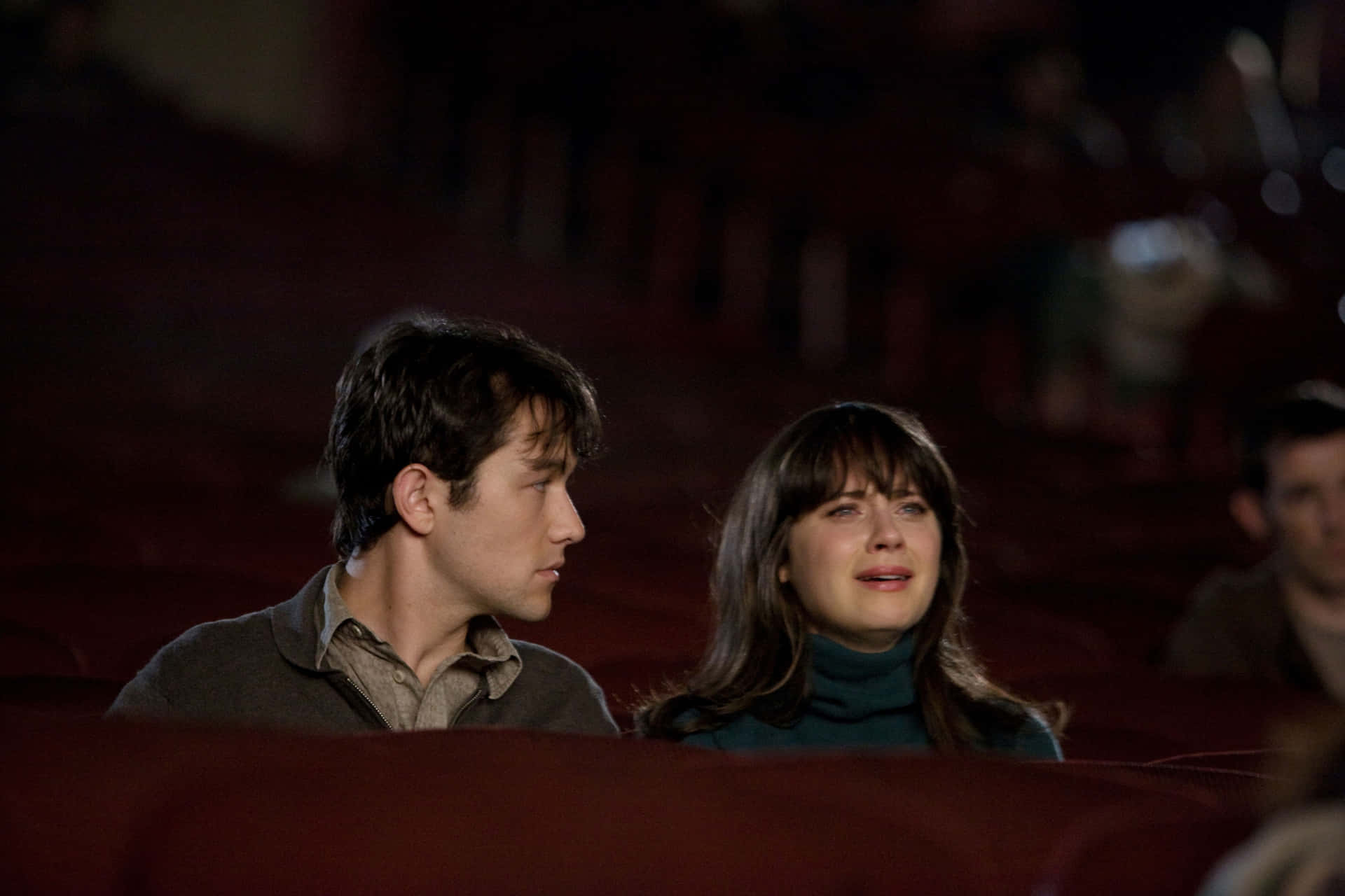 A Man And Woman Sitting In A Theater Watching A Movie