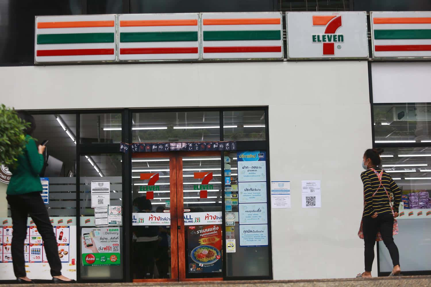 A Woman Walks Past A 7-eleven Store