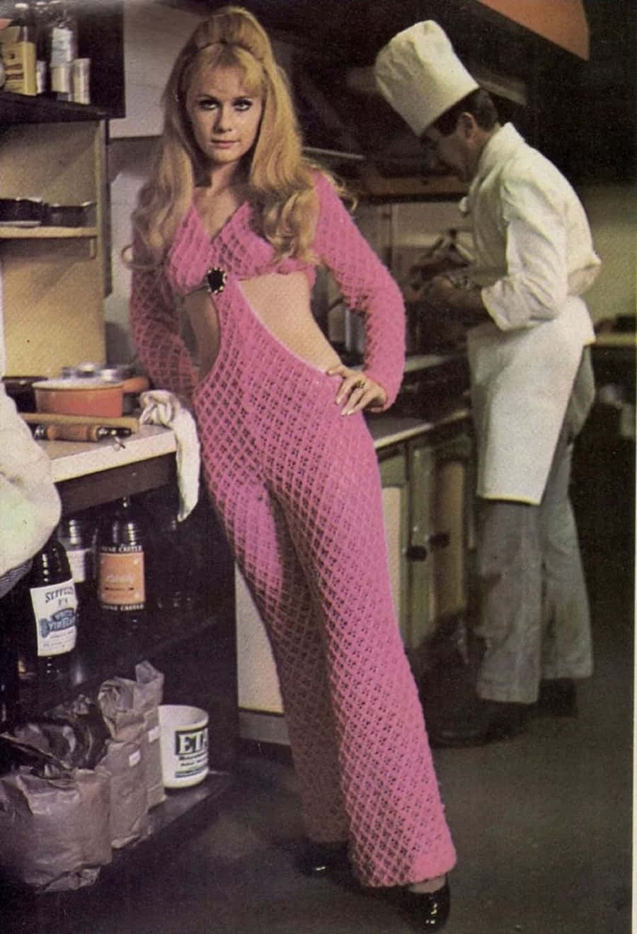 A Woman In A Pink Jumpsuit Standing Next To A Chef