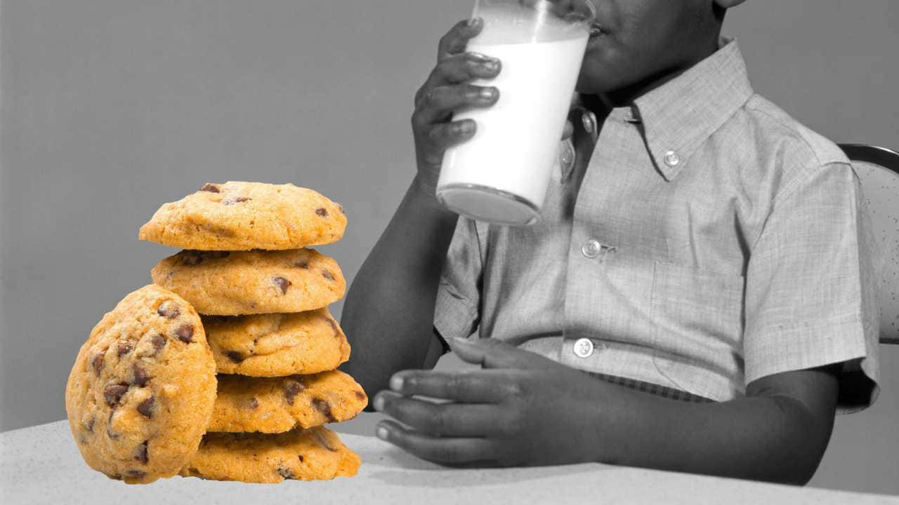 a boy drinking milk from a glass of cookies