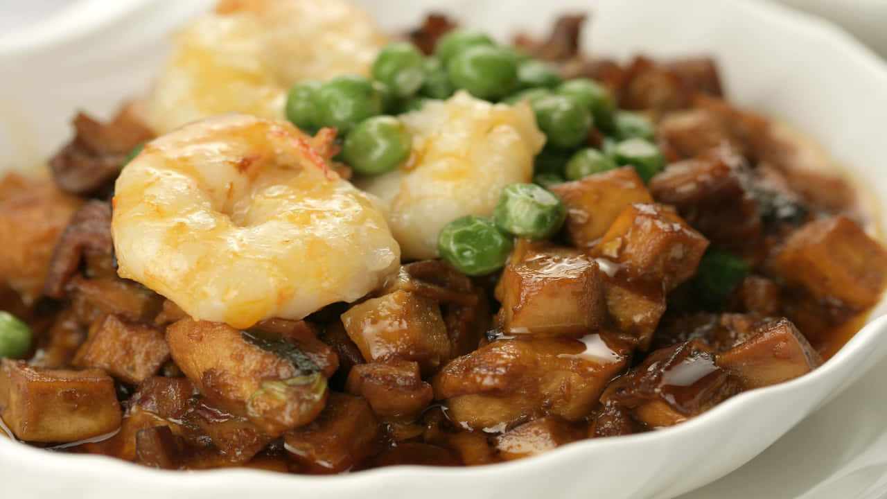 A Bowl Of Food With Shrimp, Peas And Meat