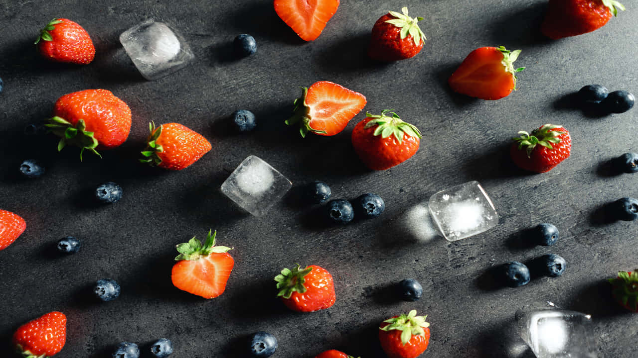 A Group Of Strawberries And Blueberries With Ice Cubes