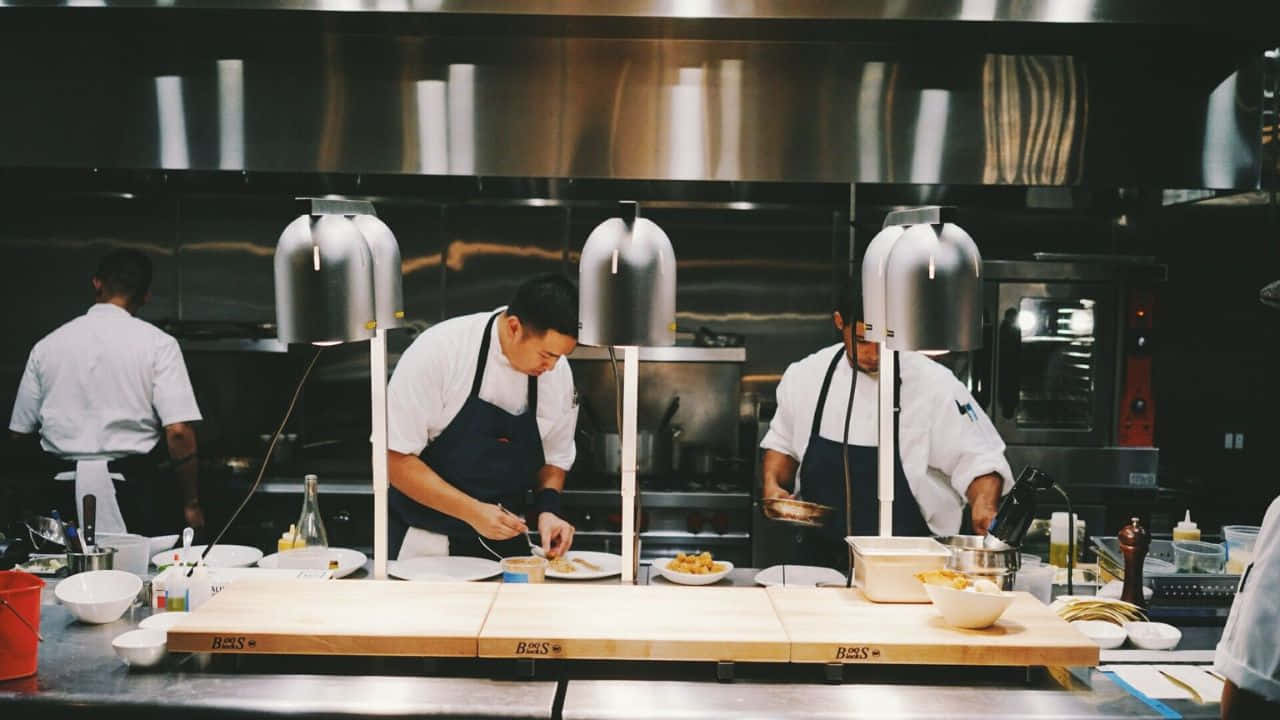 A Group Of Chefs Preparing Food In A Kitchen