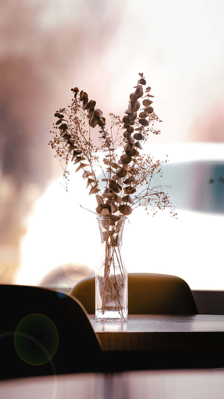 En vase med tørrede blomster på et bord