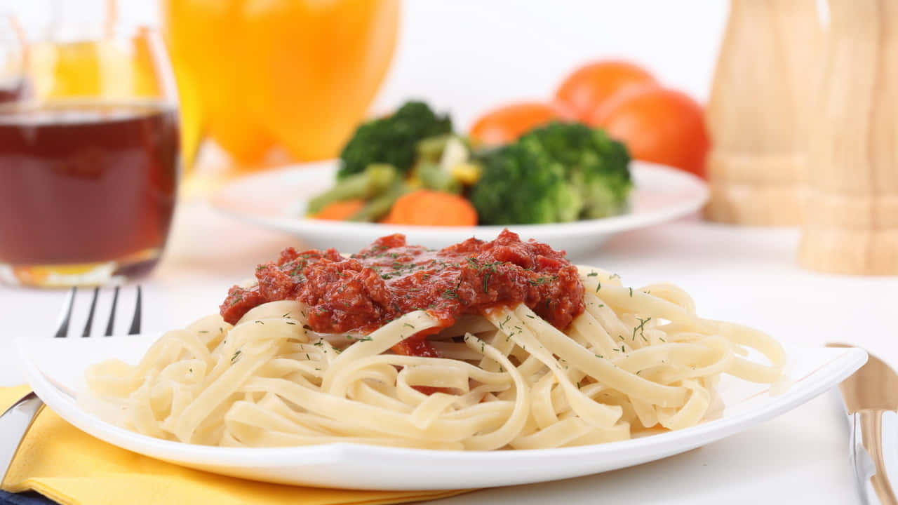 A Plate Of Spaghetti With Sauce And Vegetables
