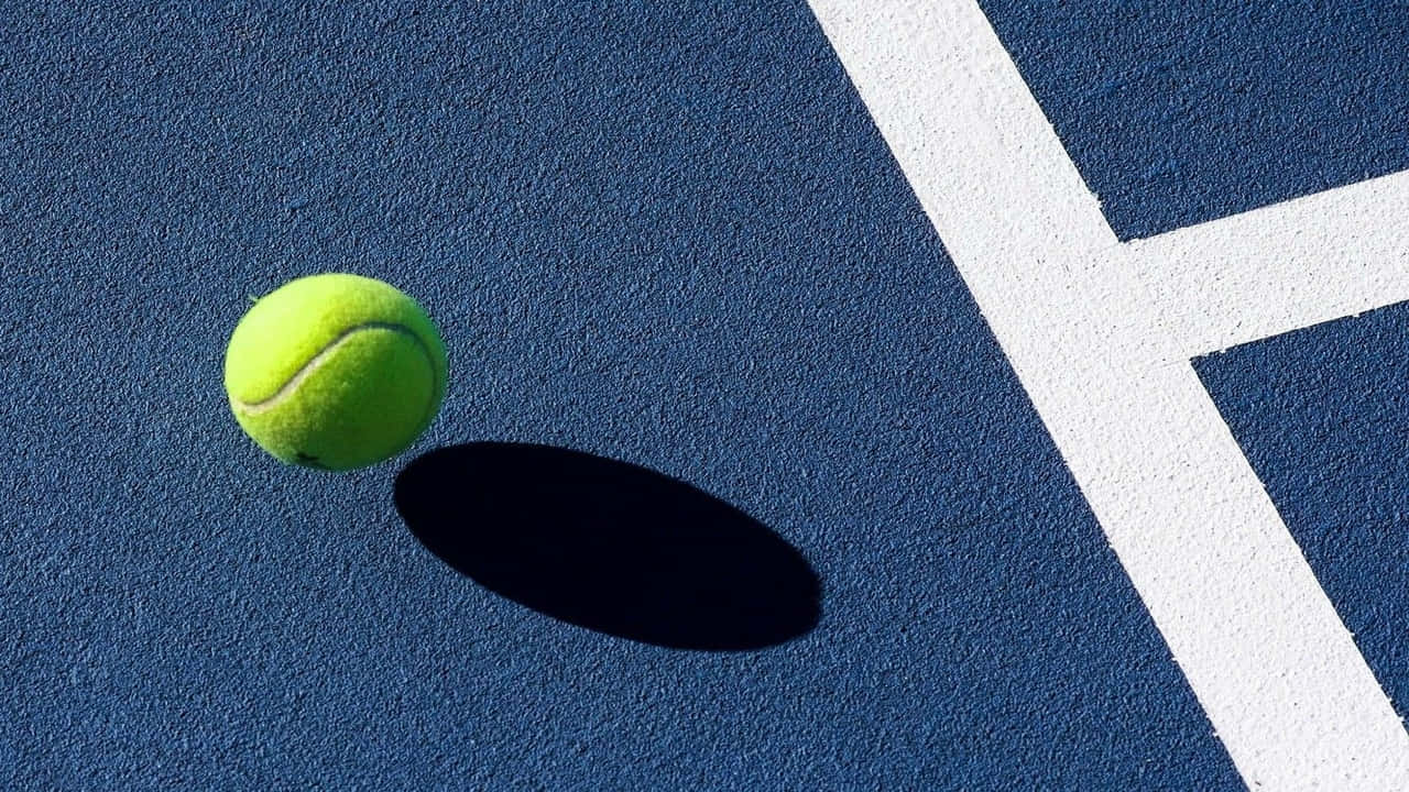 A Tennis Ball Is Sitting On A Blue And White Tennis Court