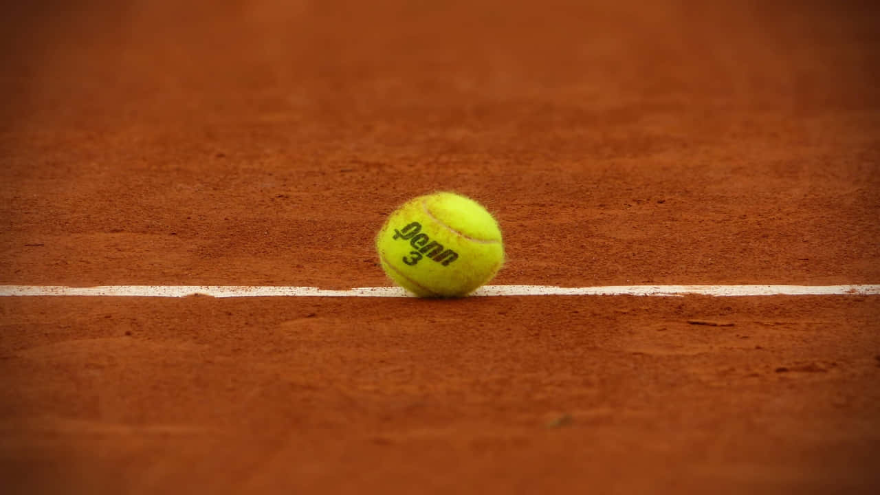 A Tennis Ball Is Sitting On A Red Clay Court