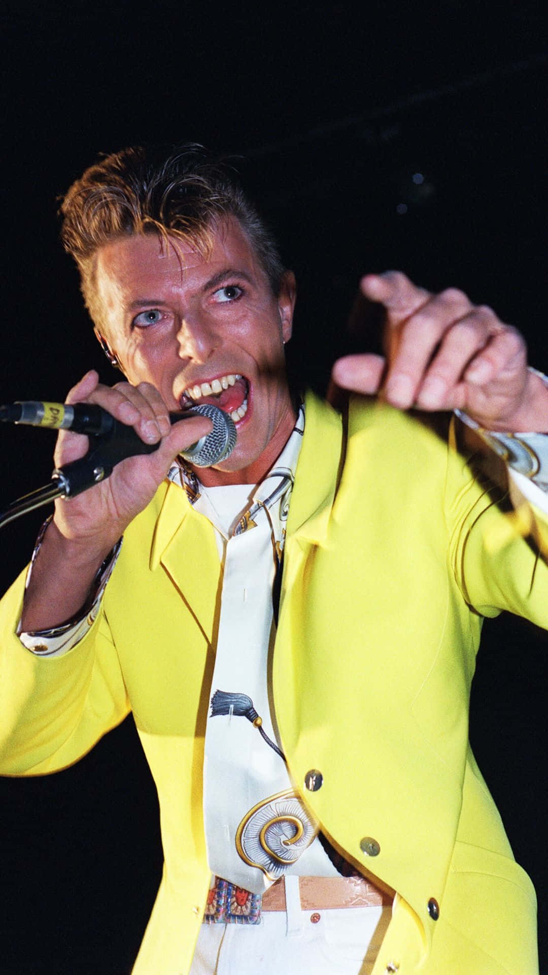 David Bowie In A Yellow Suit Singing Into A Microphone