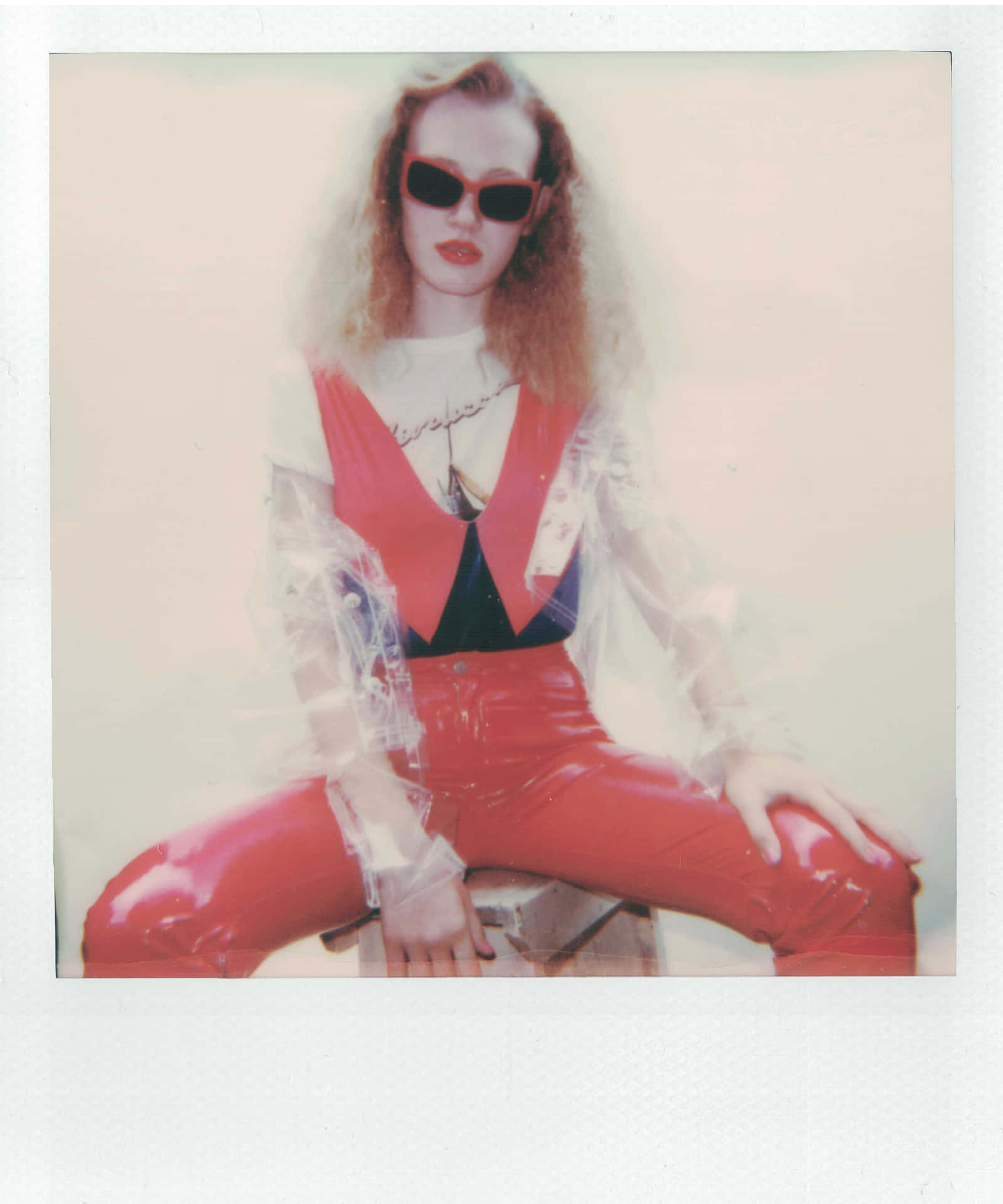 A Woman In Red Pants And Sunglasses Sitting On A Stool