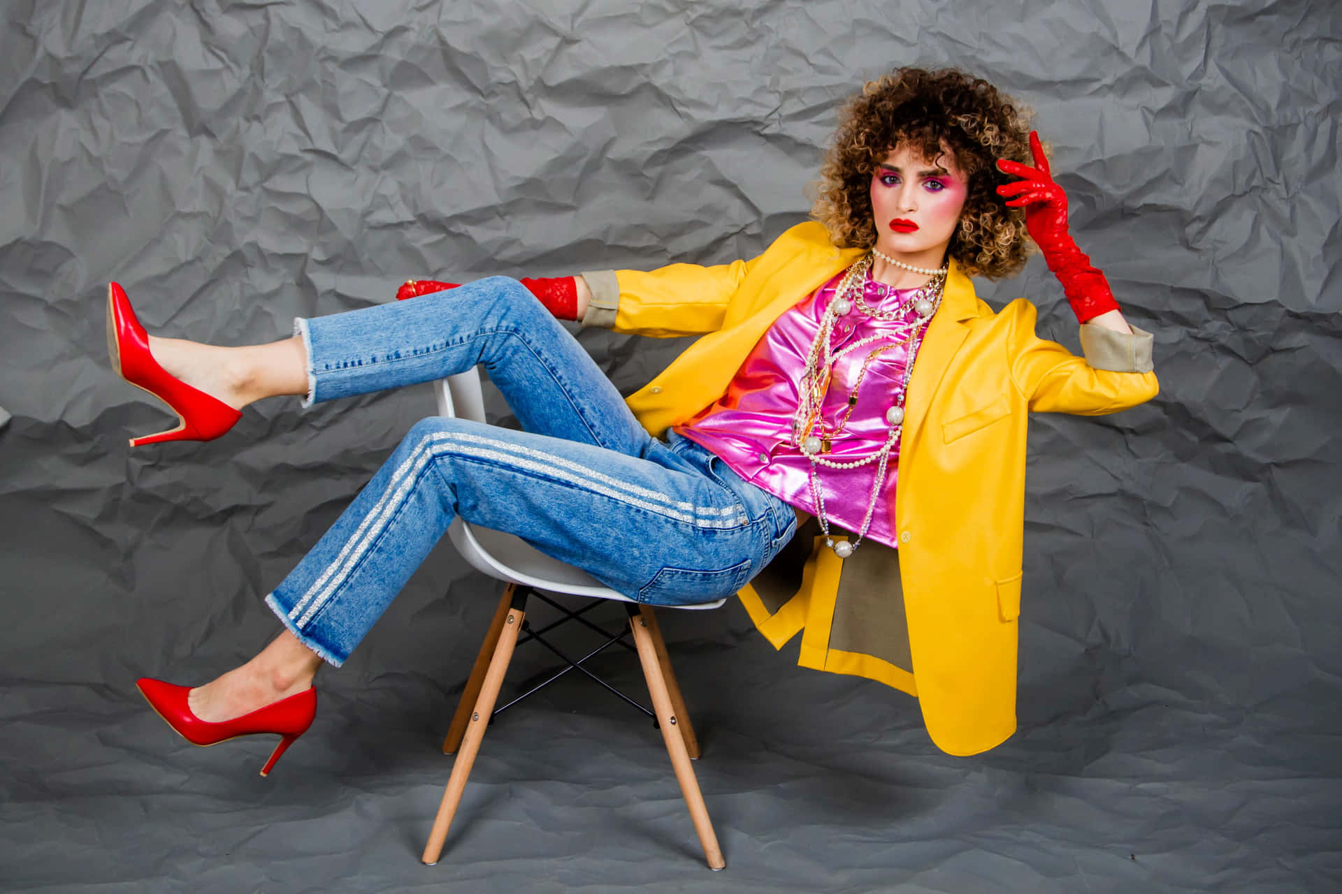 A Woman In A Yellow Jacket And Red Heels Is Sitting On A Chair