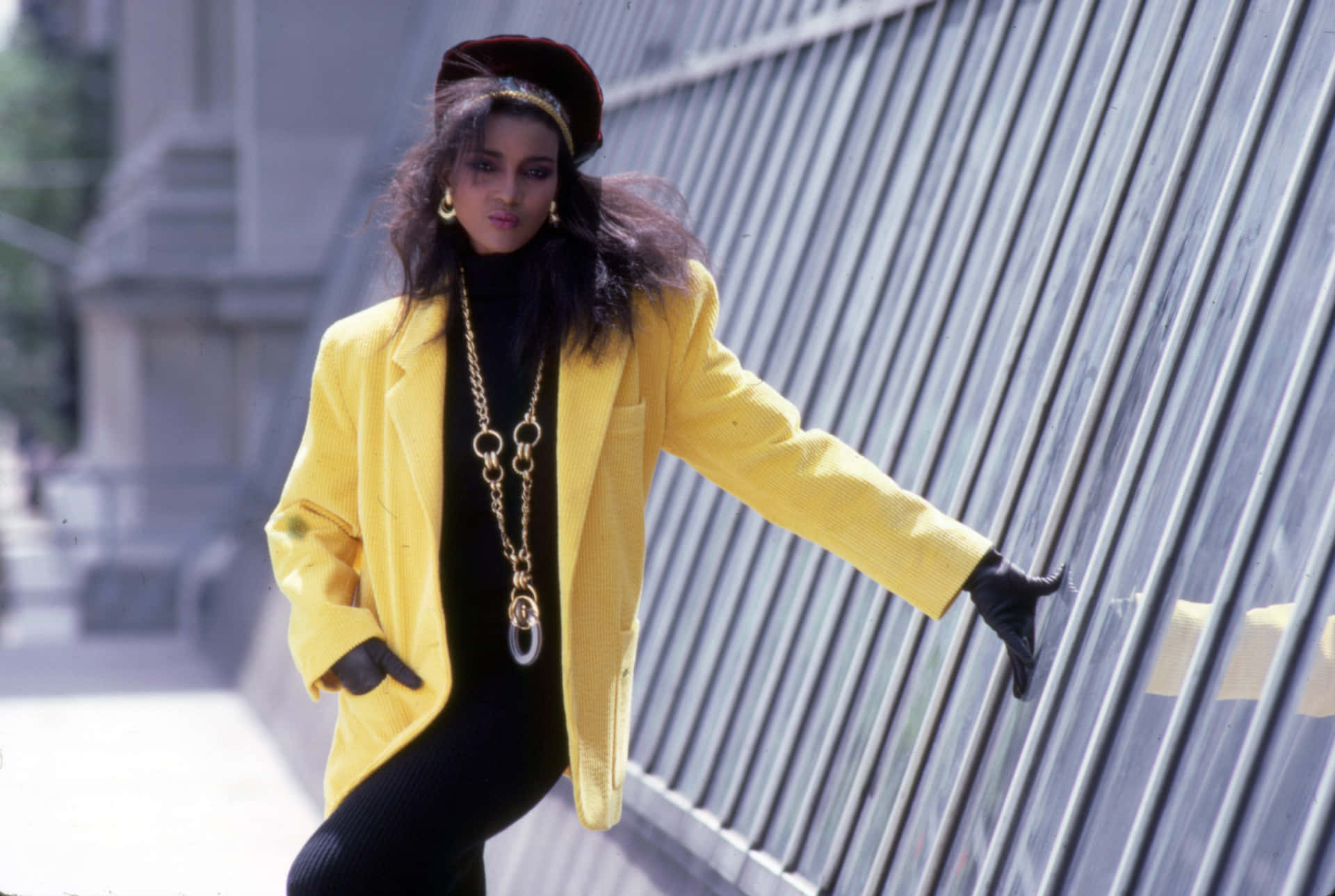 A Woman In A Yellow Jacket Leaning Against A Wall