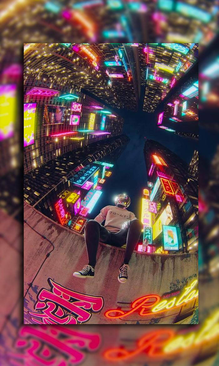 A Man Sitting On A Ledge In Front Of Neon Lights Wallpaper
