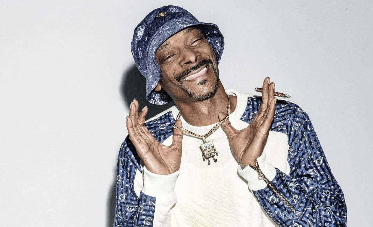 Snoop Dogg Is Smiling While Wearing A Blue Hat Wallpaper
