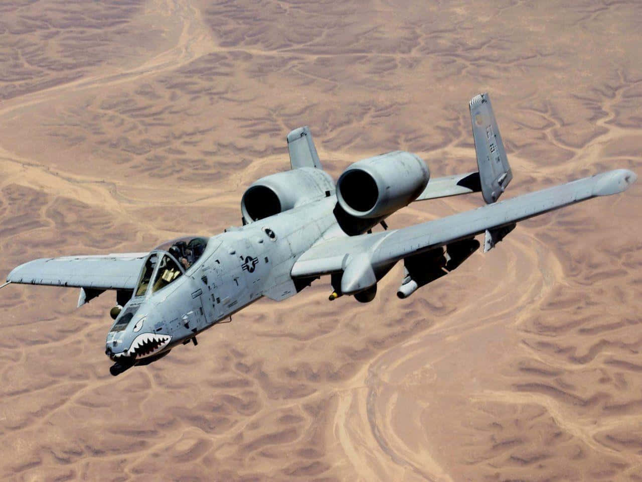 A Military Jet Flying Over A Desert Wallpaper