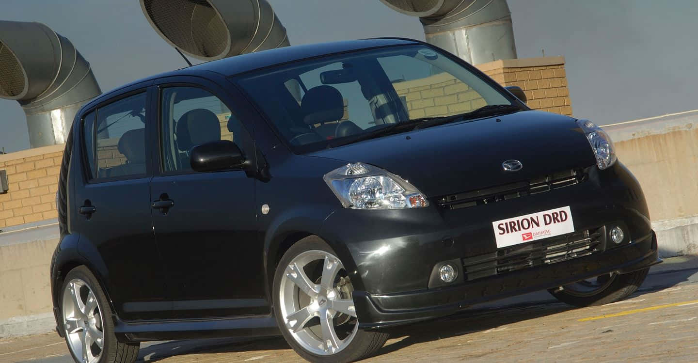 A Compact Yet Stylish Daihatsu Sirion Parked Conveniently On The Street. Wallpaper