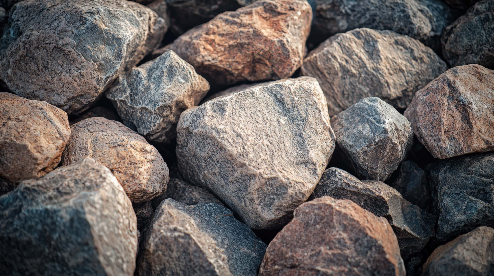 A Detailed Close-up Of Various Rough, Jagged Rocks With Natural Earthy Tones Wallpaper