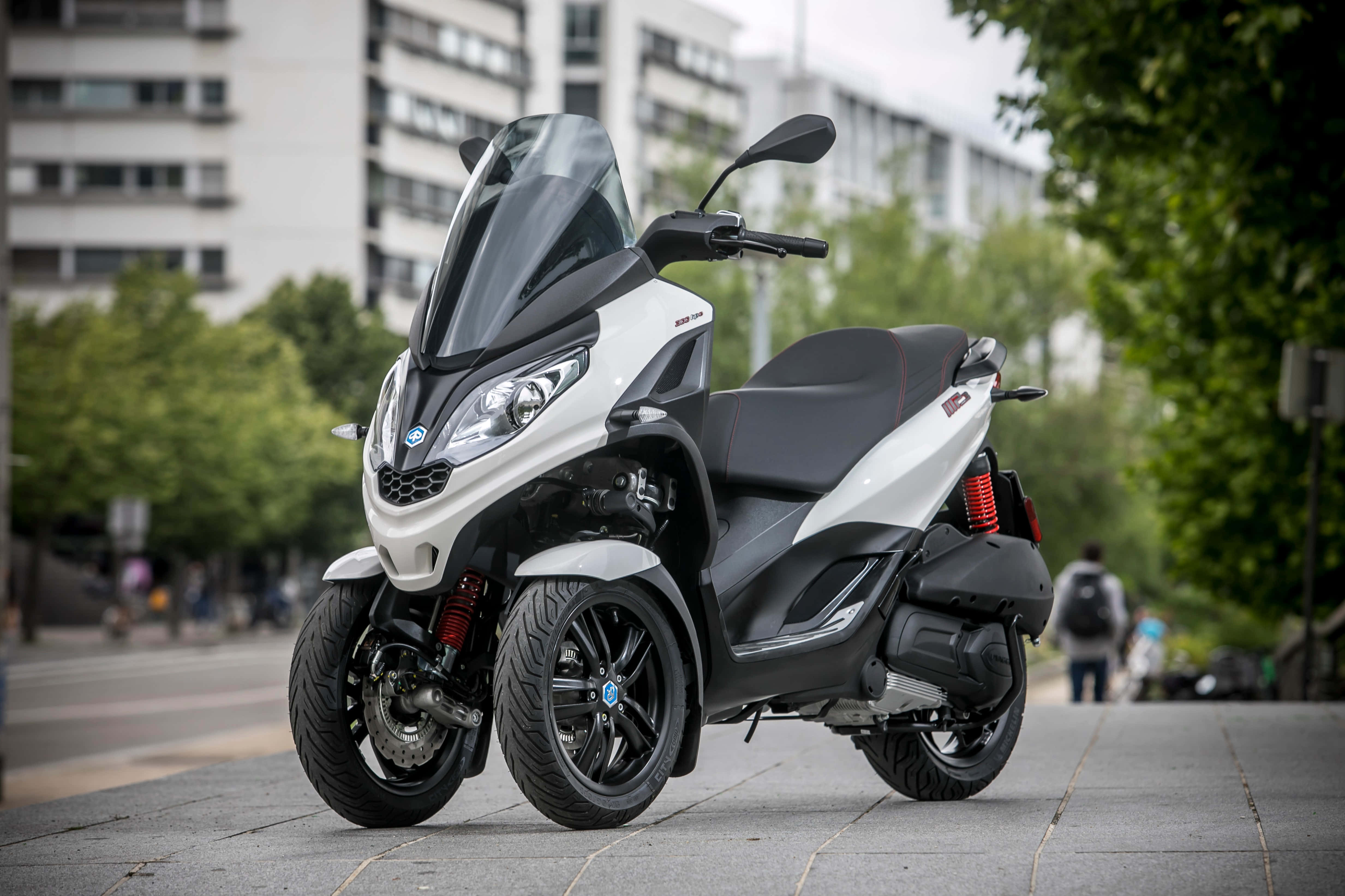 A Luxurious, Black Piaggio Motor Scooter Parked In A Scenic Cityscape. Wallpaper