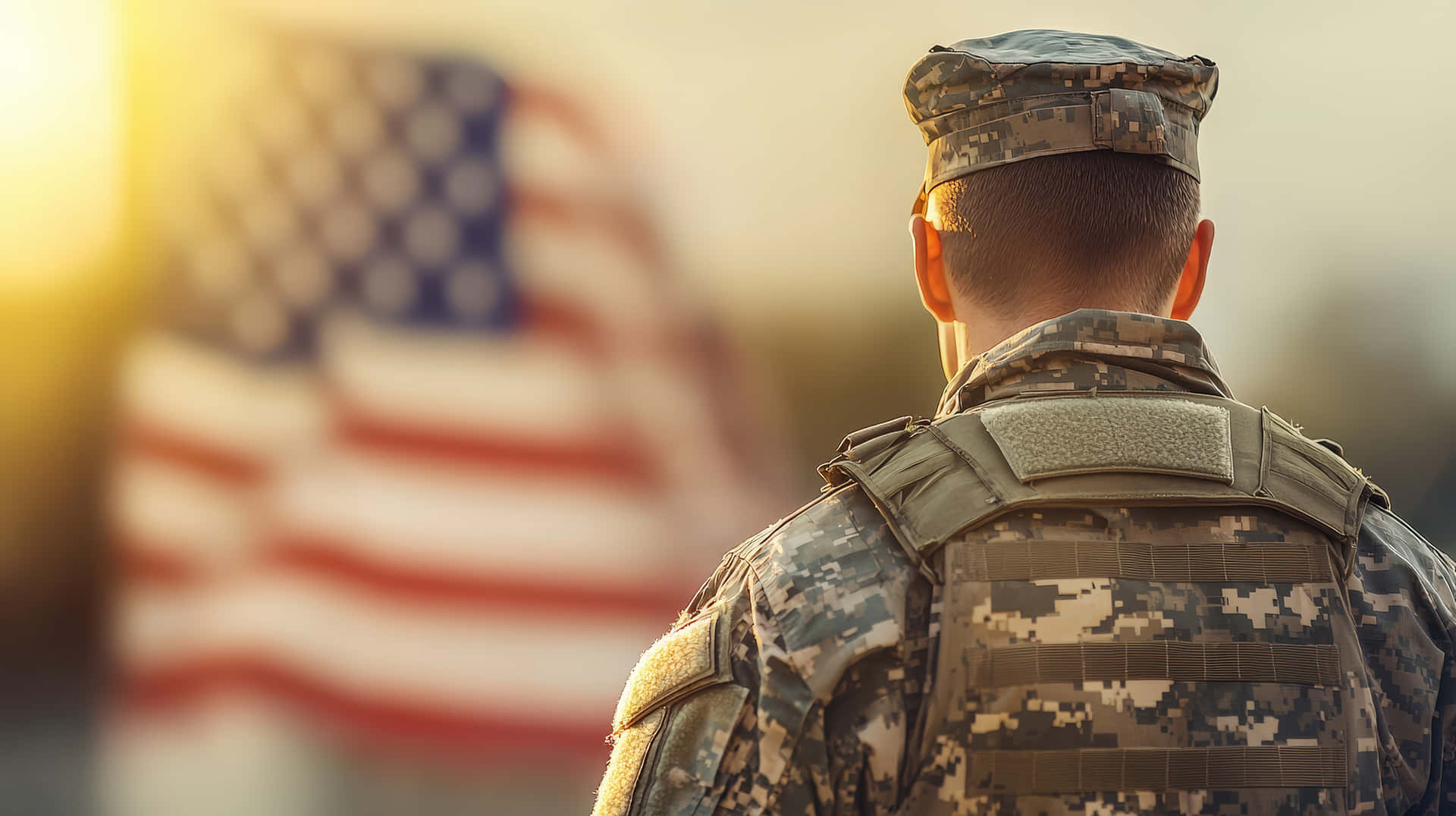 A Military Soldier In Camouflage Uniform Stands With His Back Turned, Looking At The American Flag Wallpaper