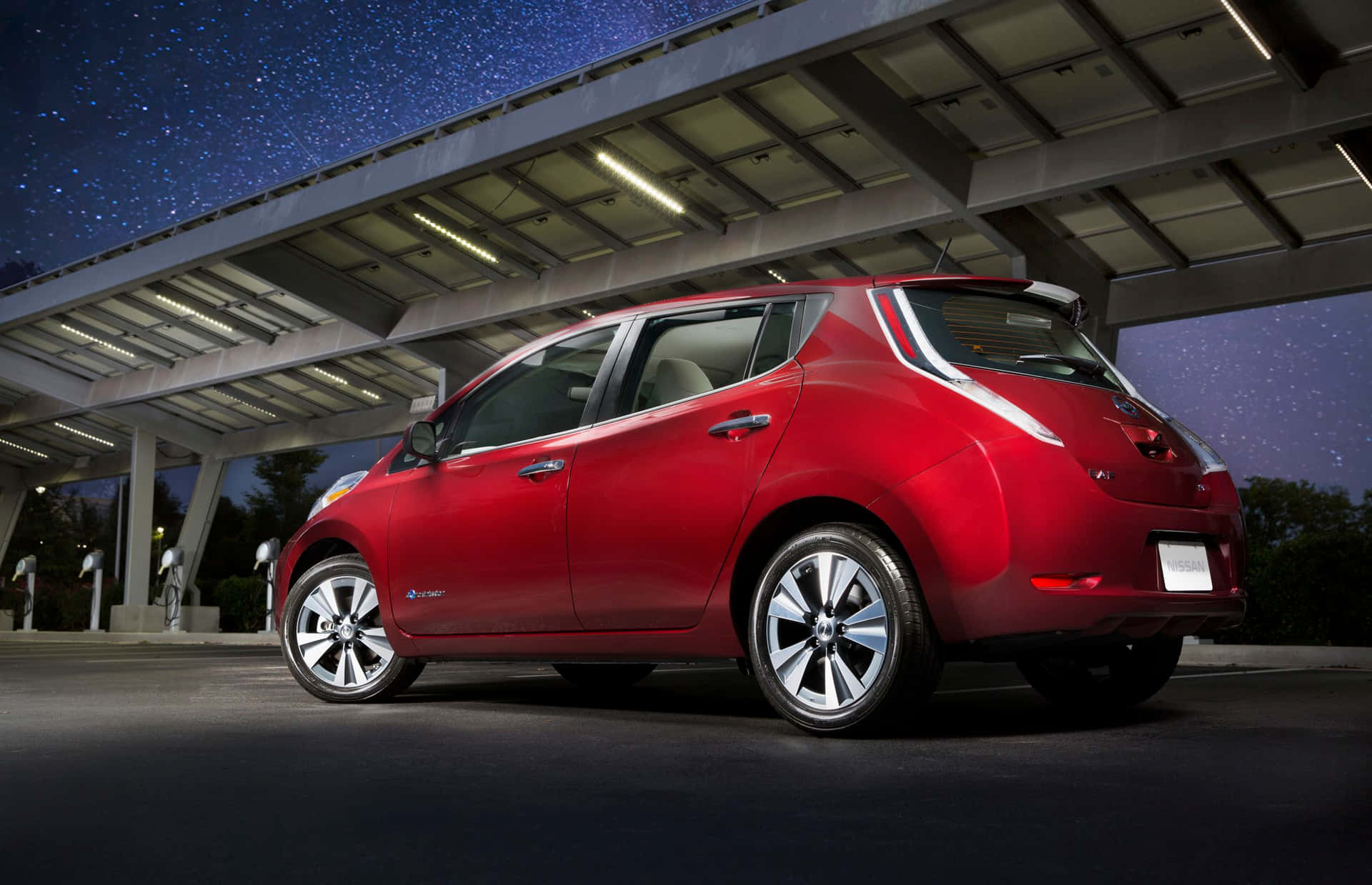 A Pristine Nissan Leaf Electric Vehicle Poised On A Scenic Road. Wallpaper