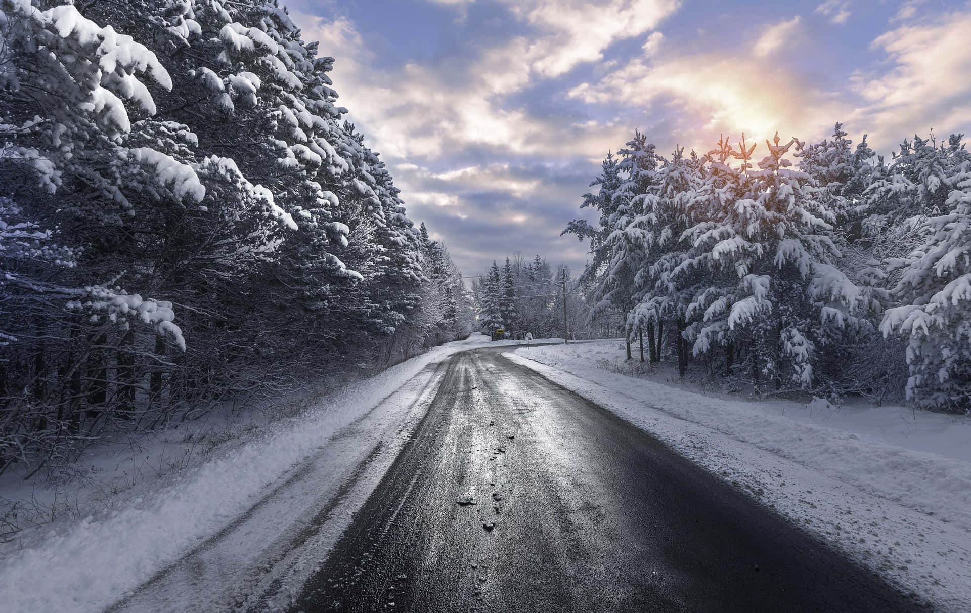A Serene Journey Along The Snowy Road Wallpaper