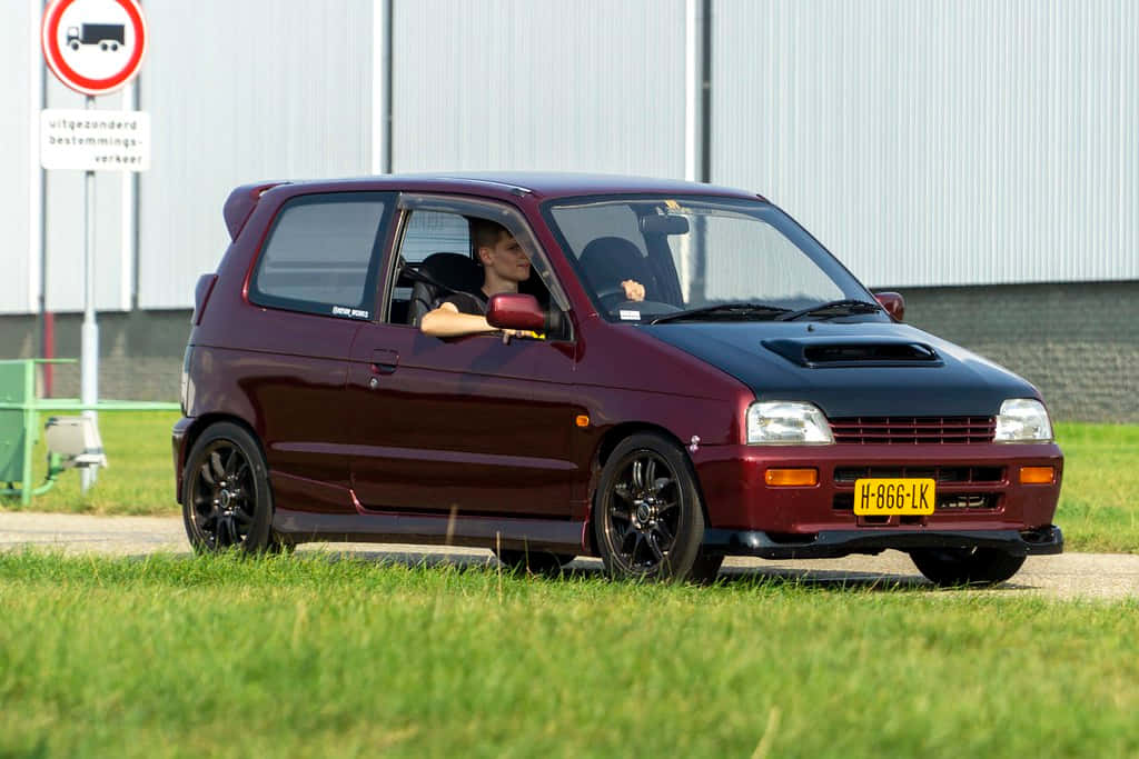 A Sleek Suzuki Alto Standing Out In The Urban Landscape Wallpaper