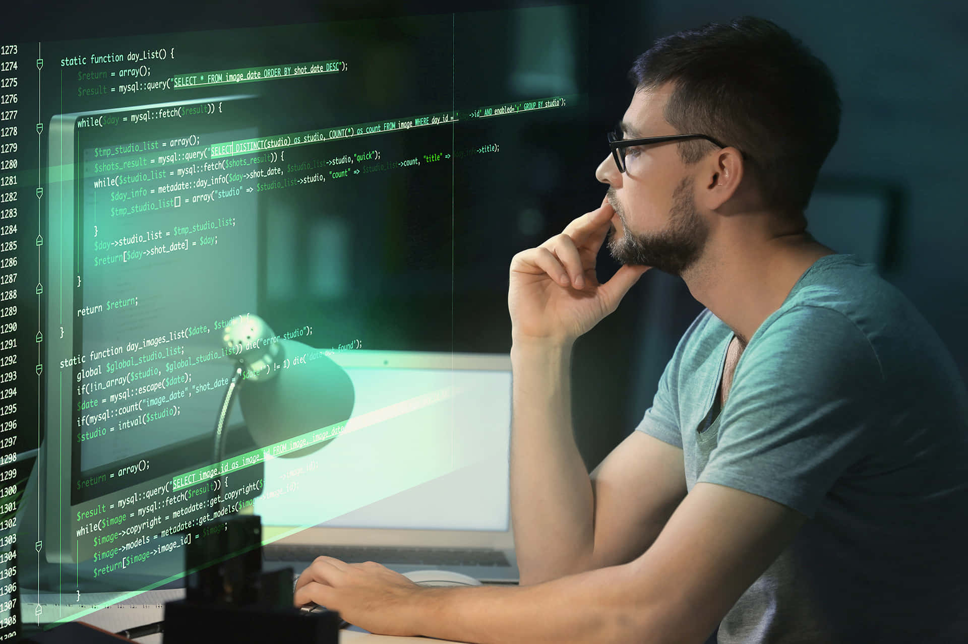 A Software Engineer Working on a Program Picture — A focused programmer in glasses contemplates code floating in green digital light over his desk in a dimly lit room.