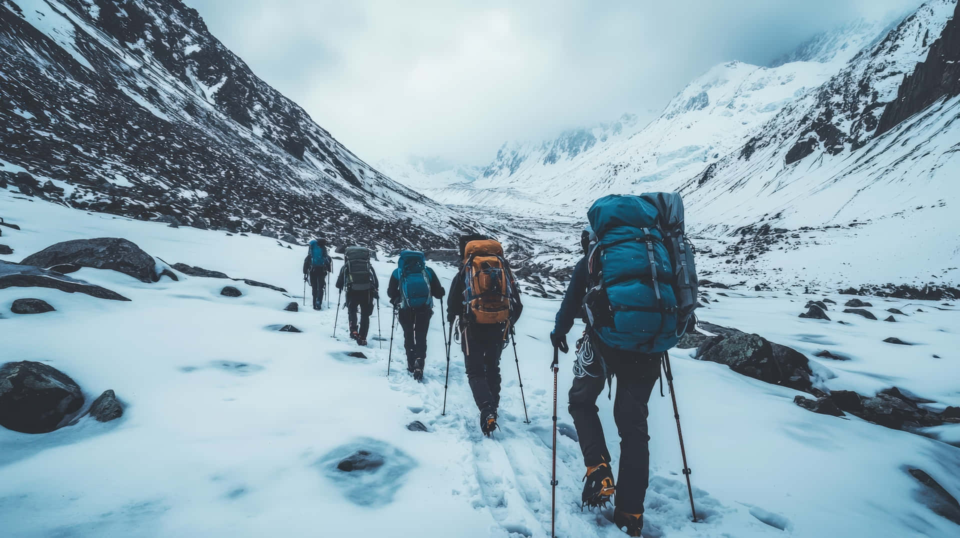 A Team Of Hikers With Backpacks And Trekking Poles Journey Through A Rugged, Snow-covered Mountain Wallpaper