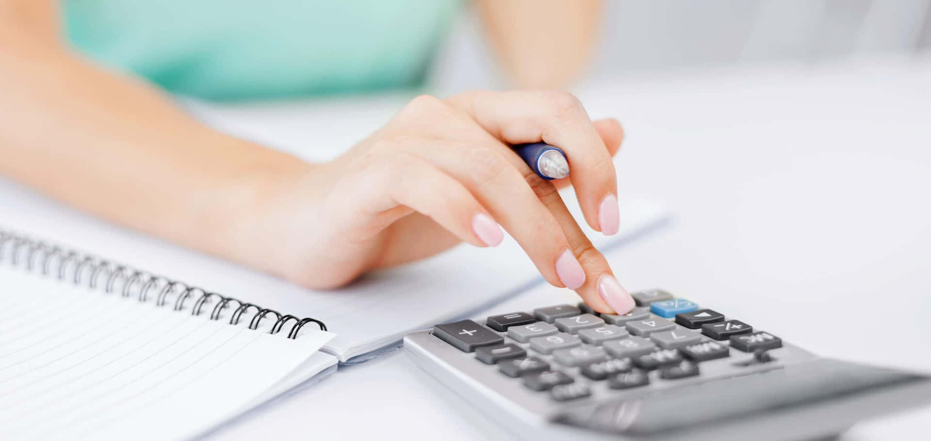 A Woman Is Using A Calculator On A Desk