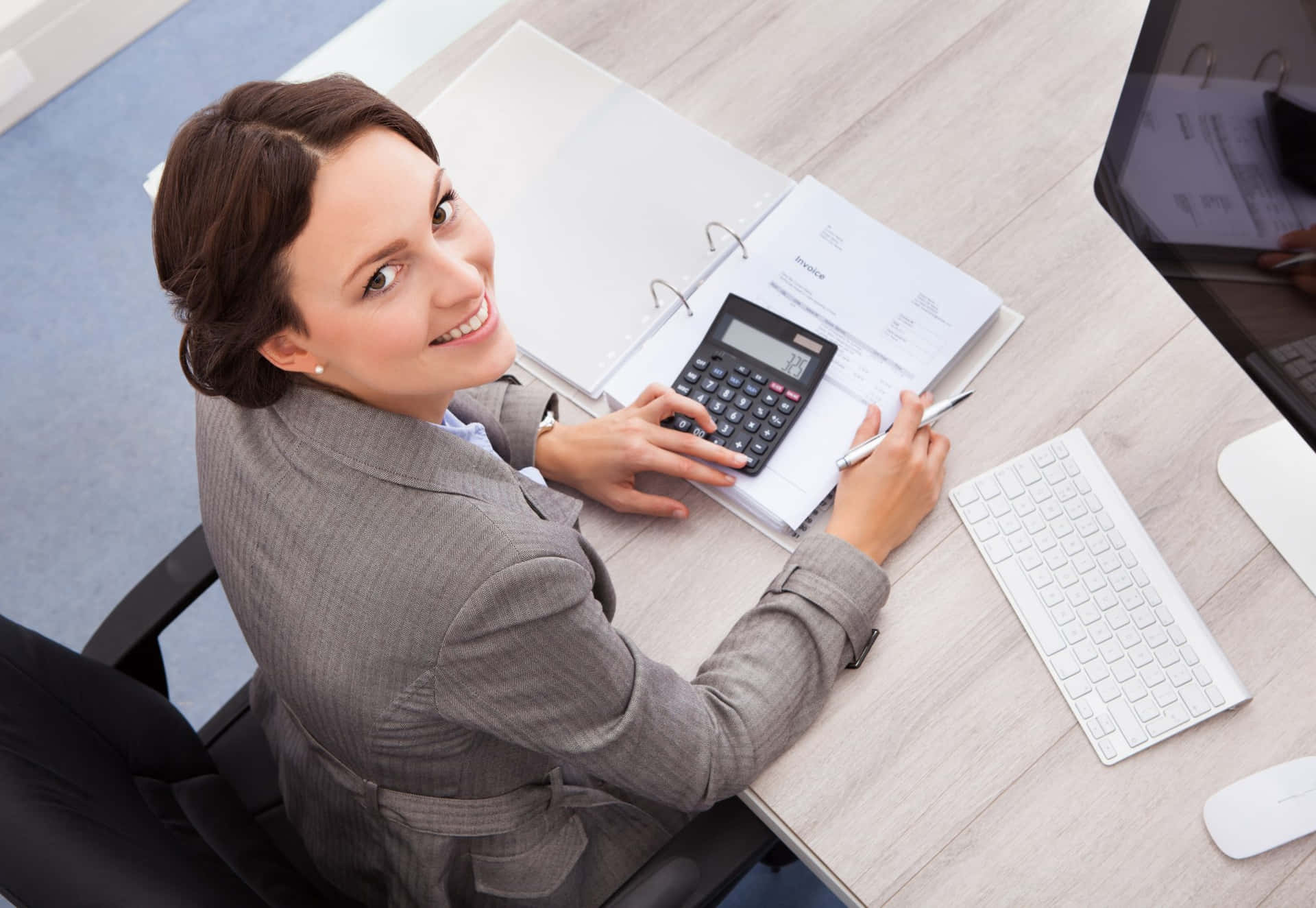 A Woman Is Sitting At Her Desk With A Calculator