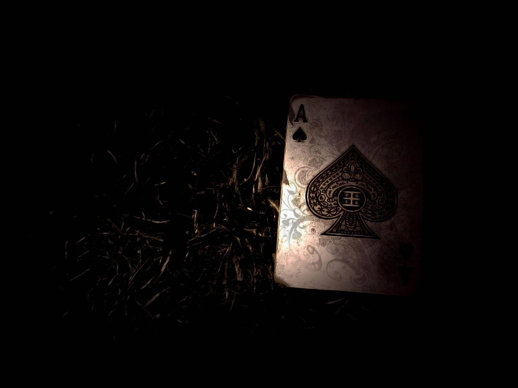 Et spillekort sidder på jorden i mørket Wallpaper