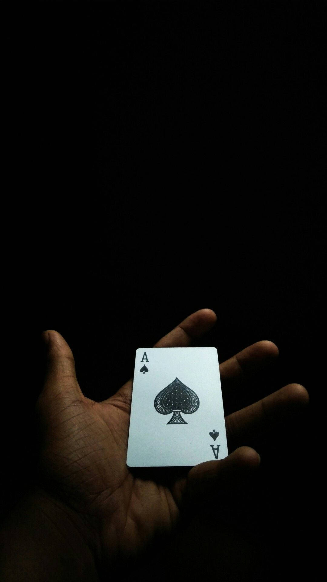 En person der holder et spillekort i mørket. Wallpaper