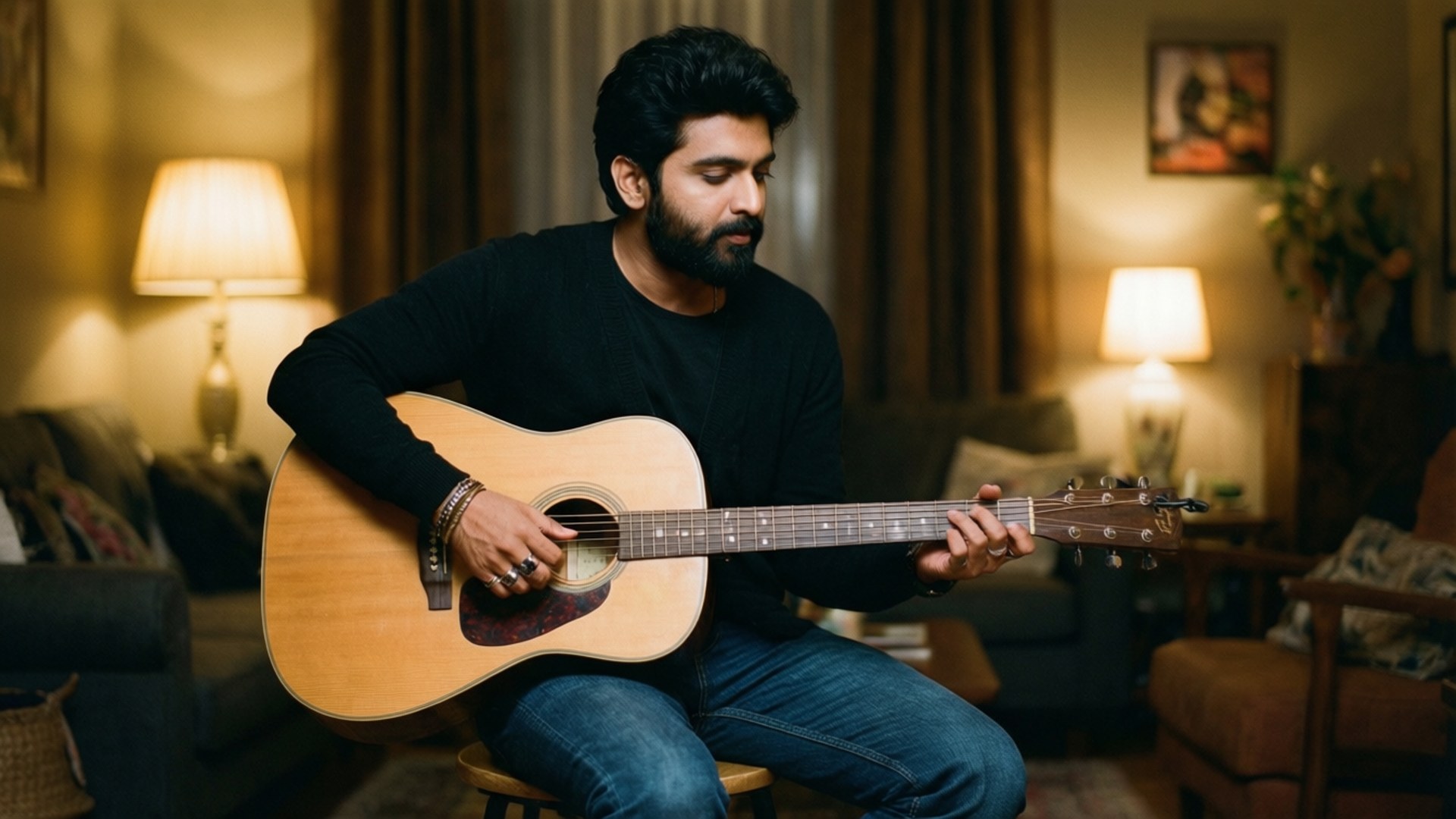 Darshan Raval playing acoustic guitar in a cozy indoor setting.
