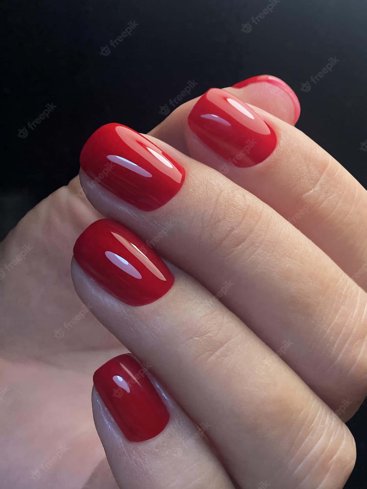 A Woman's Hand Holding A Red Nail Polish Wallpaper