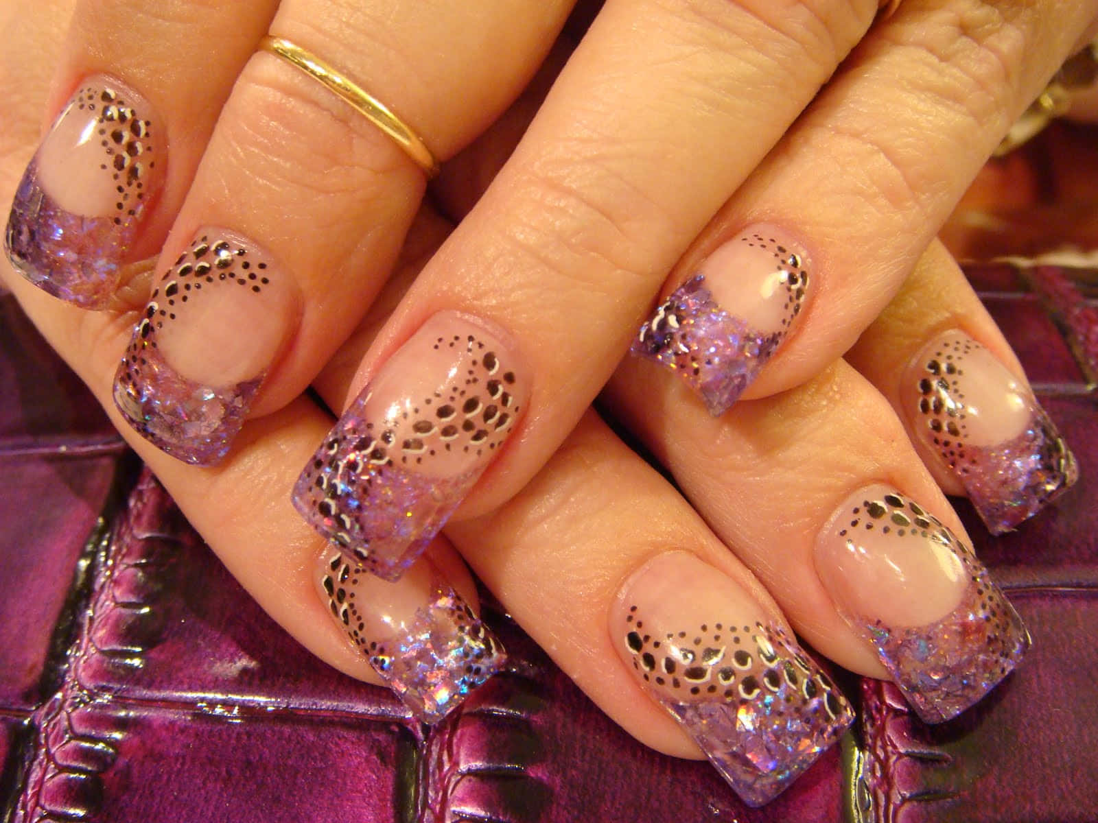 A Woman's Hand With Purple And Black Nail Designs Wallpaper