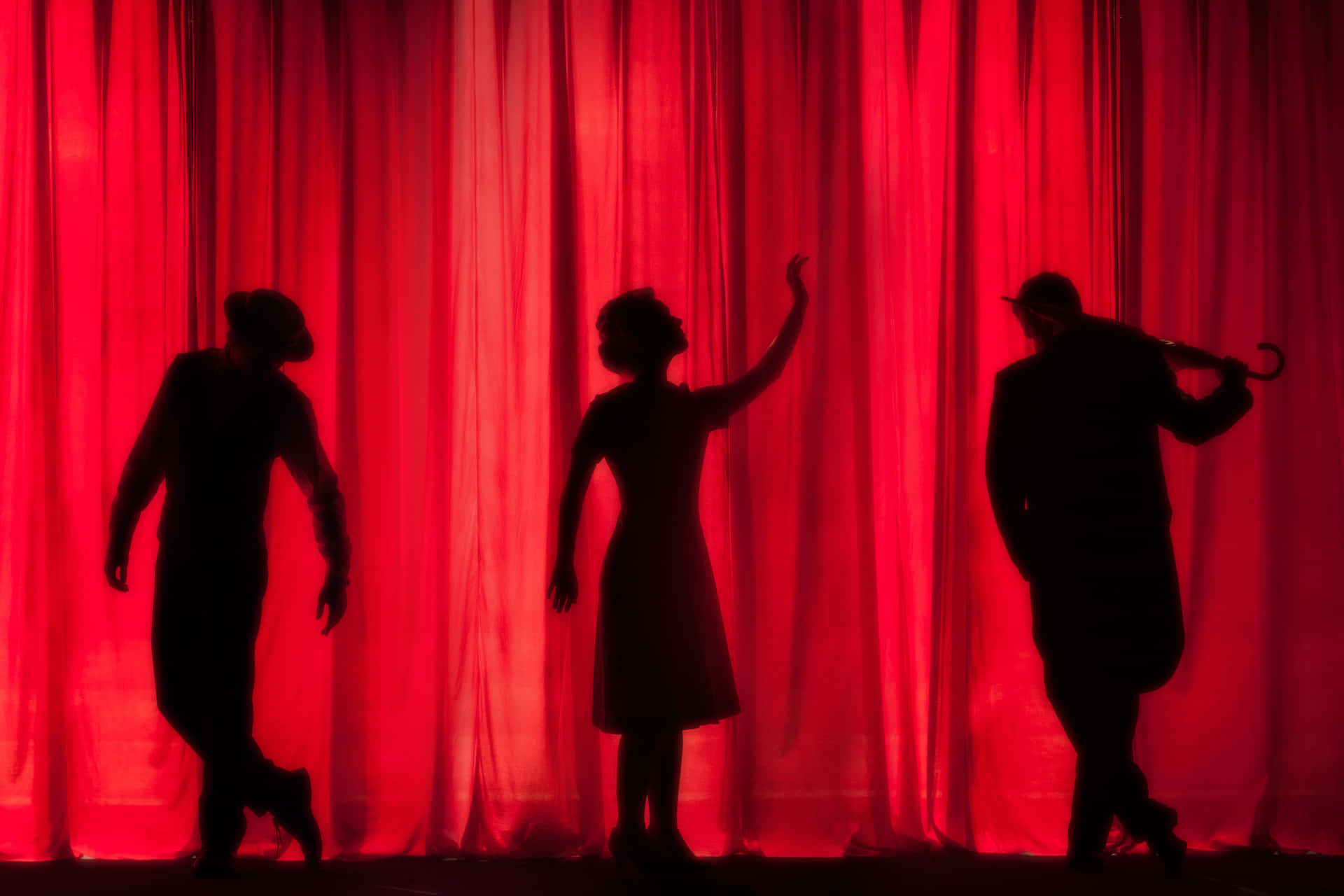 Silhouettes Of People In Front Of A Red Curtain Wallpaper