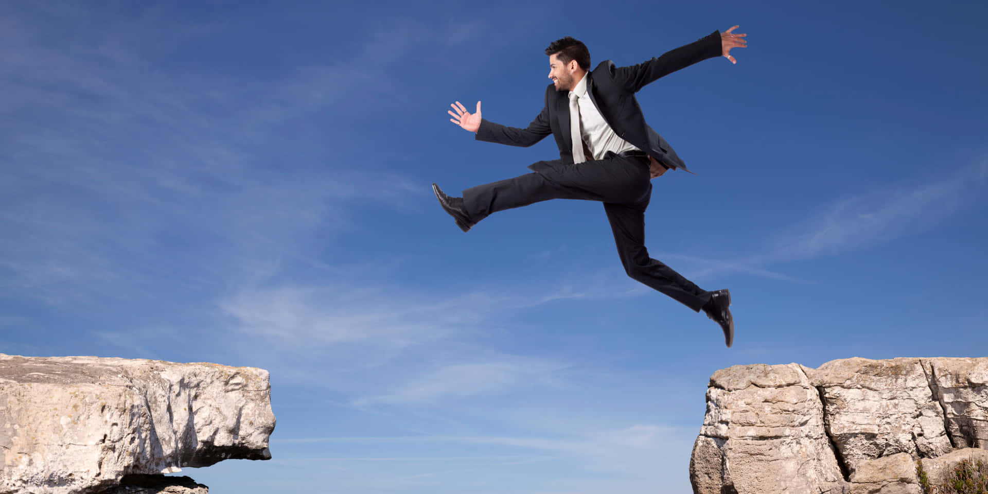 A Businessman Jumping Over A Cliff