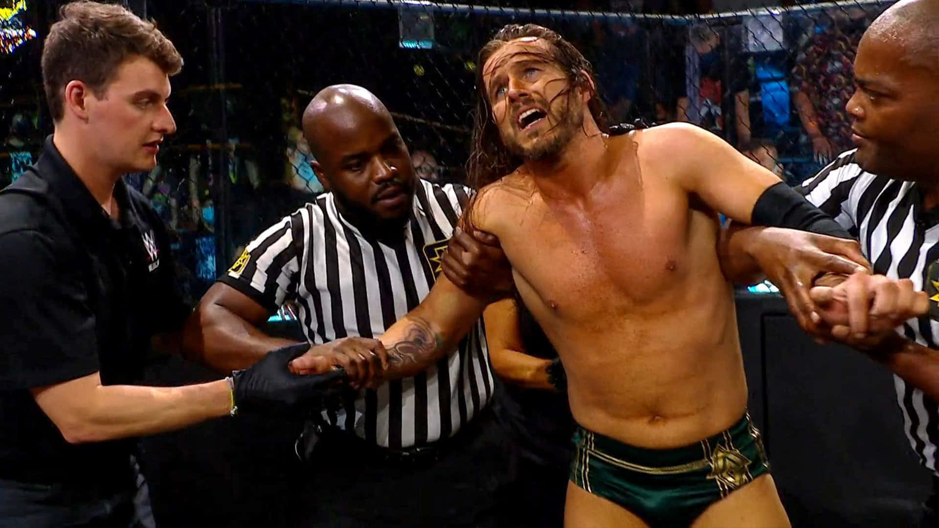 Adam Cole Being Assisted By Two Referees Wallpaper