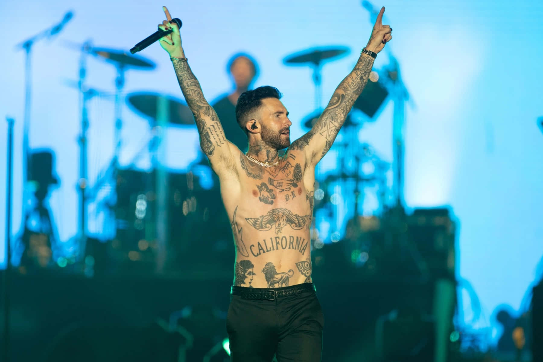 A Man With Tattoos On His Chest And Arms On Stage