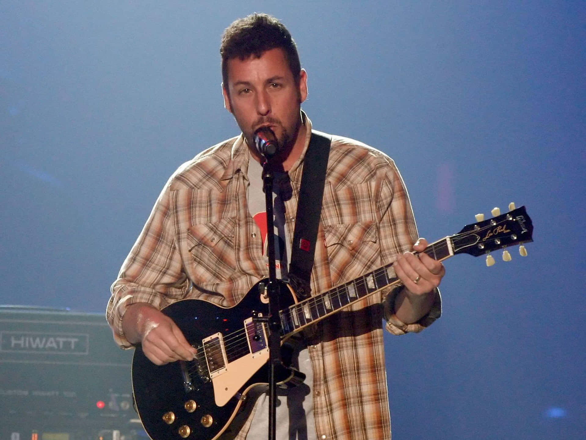 A Man In A Plaid Shirt Playing A Guitar