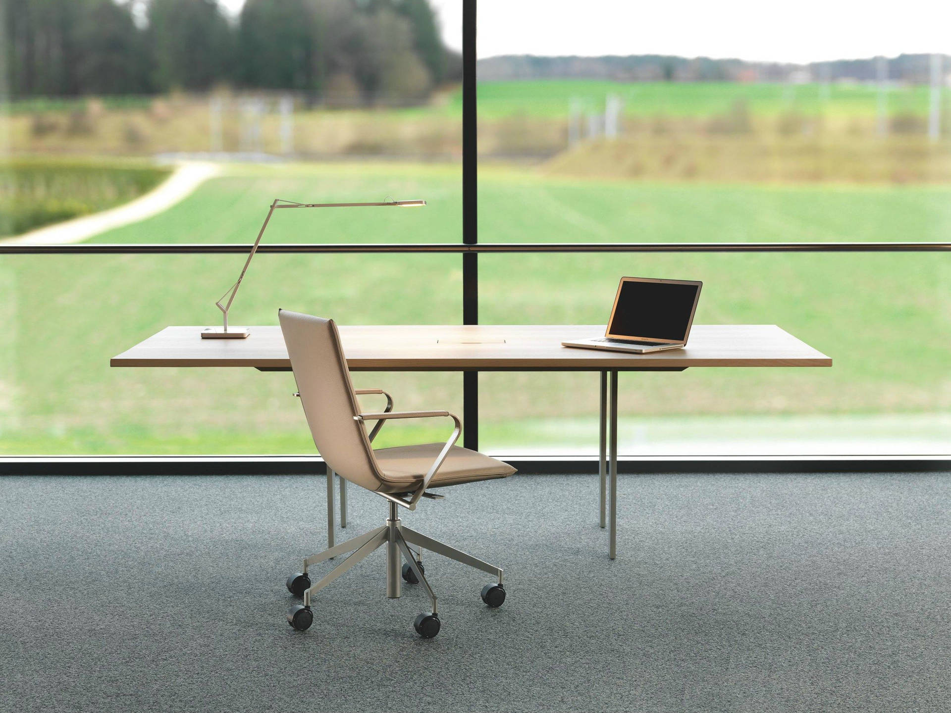 Adjustable Office Desk Set Against a Transparent Glass Wall Wallpaper