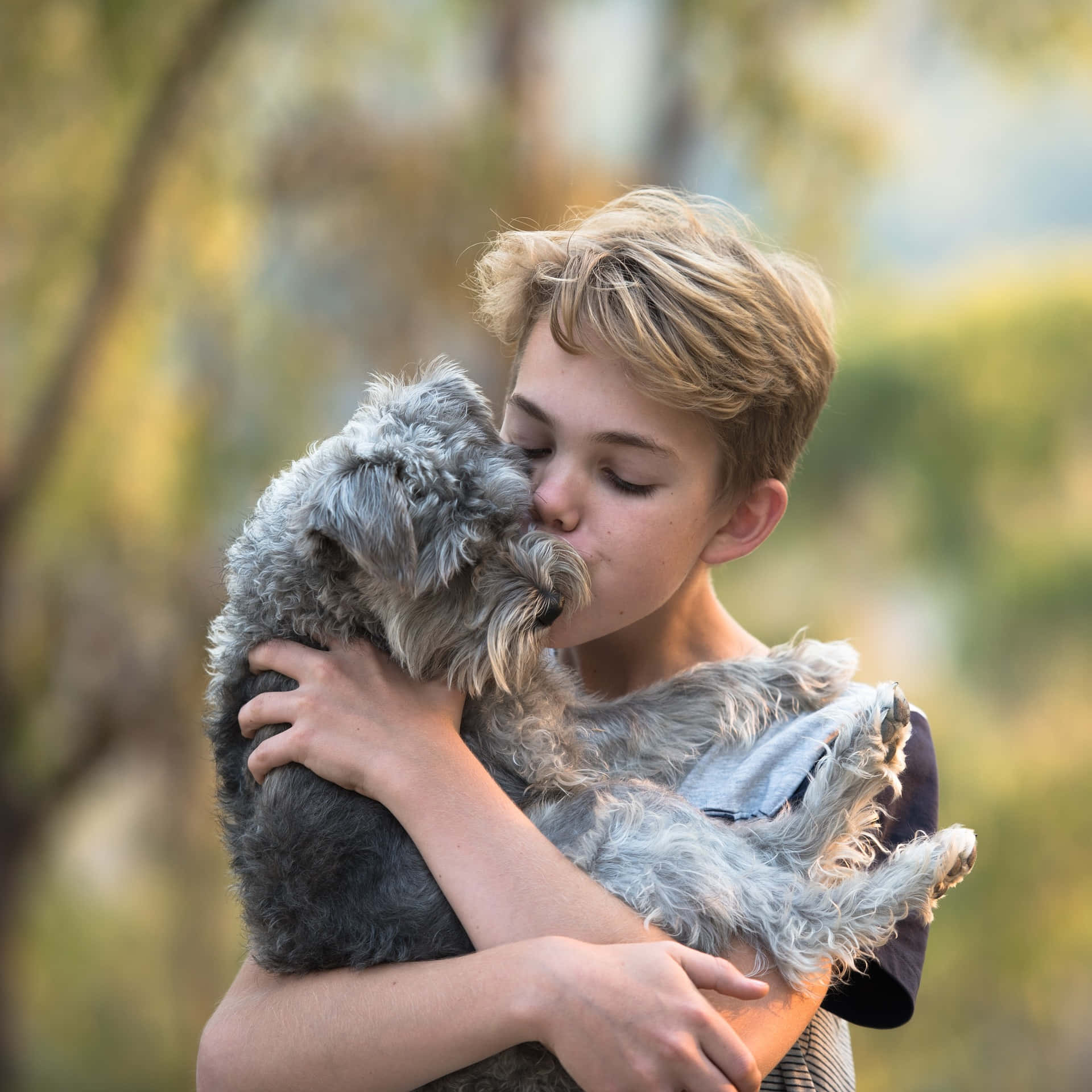 Adorable Photo Of A Young Boy Embracing And Kissing His Tangible Dog Wallpaper