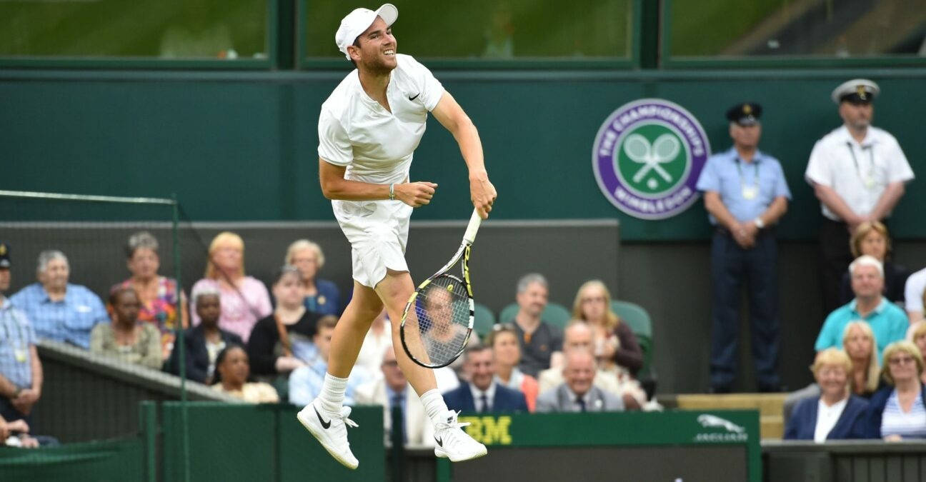 a tennis player in the air while a crowd watches Wallpaper