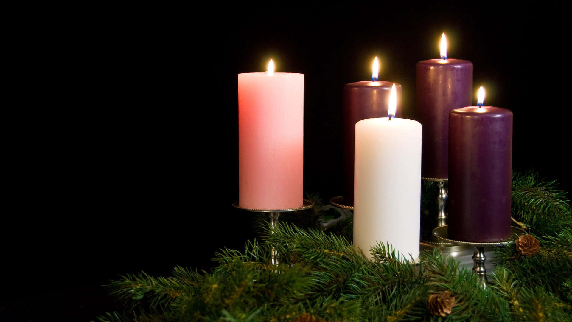 Three Candles Are Placed In A Christmas Wreath