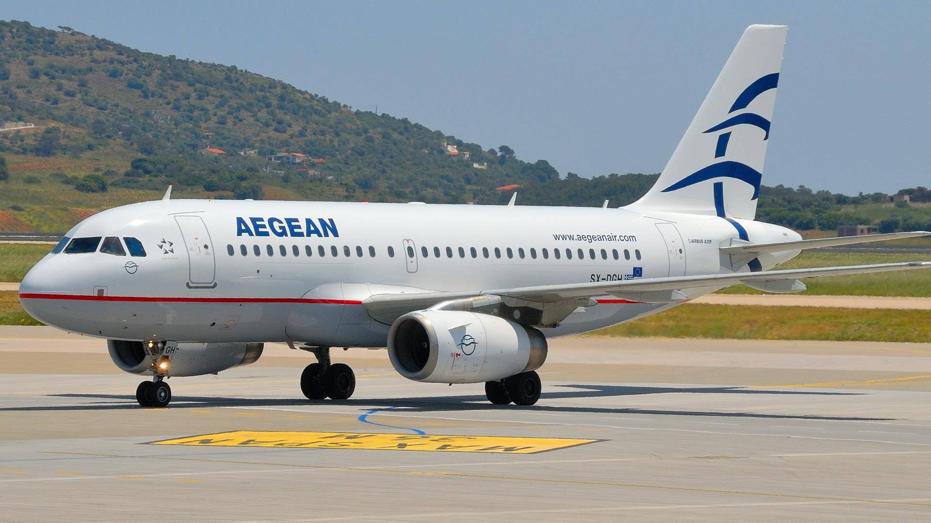 Aerolíneasde Bandera Aegean Airlines Airbus A319 Cerca De La Montaña. Fondo de pantalla