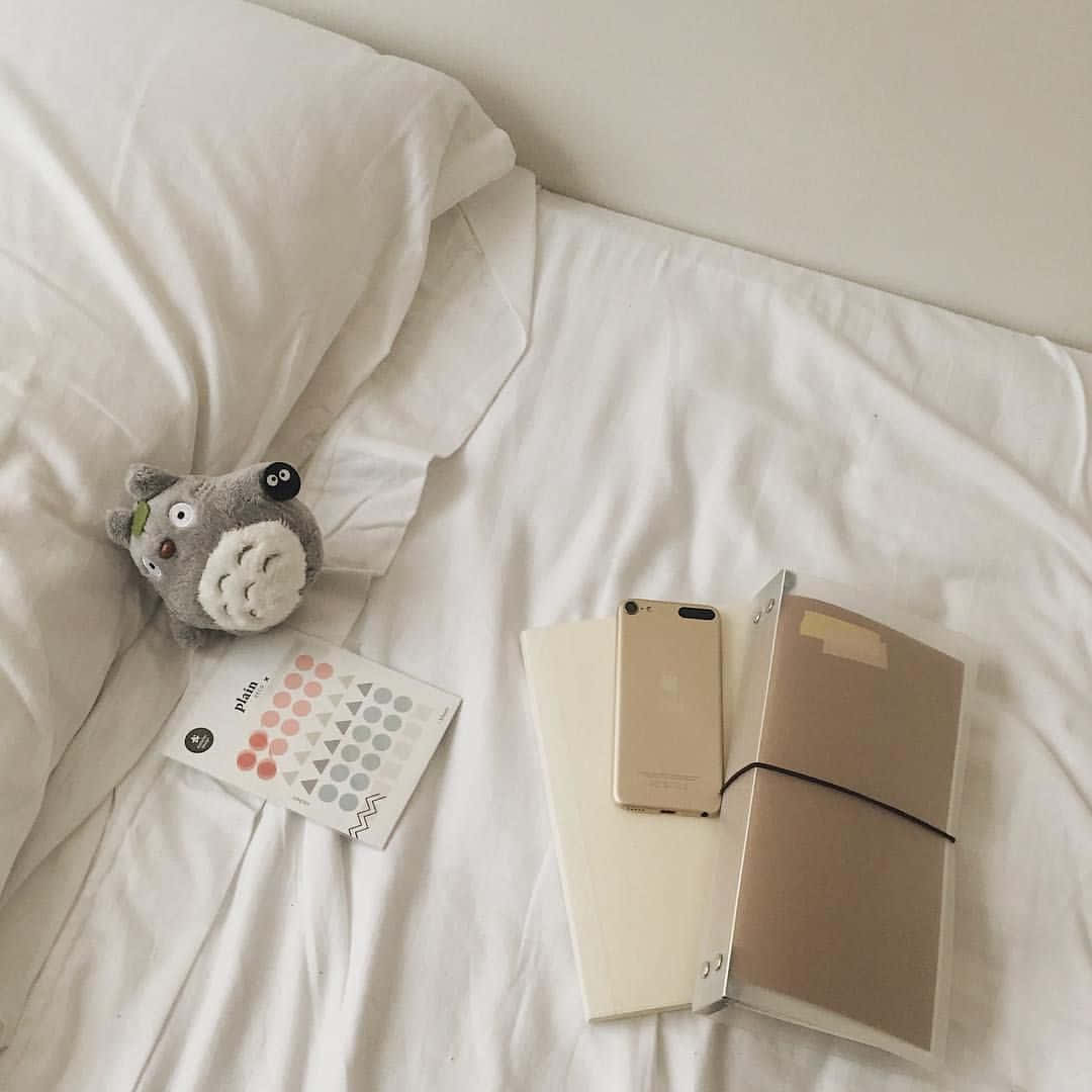 A White Bed With A Teddy Bear And A Notebook
